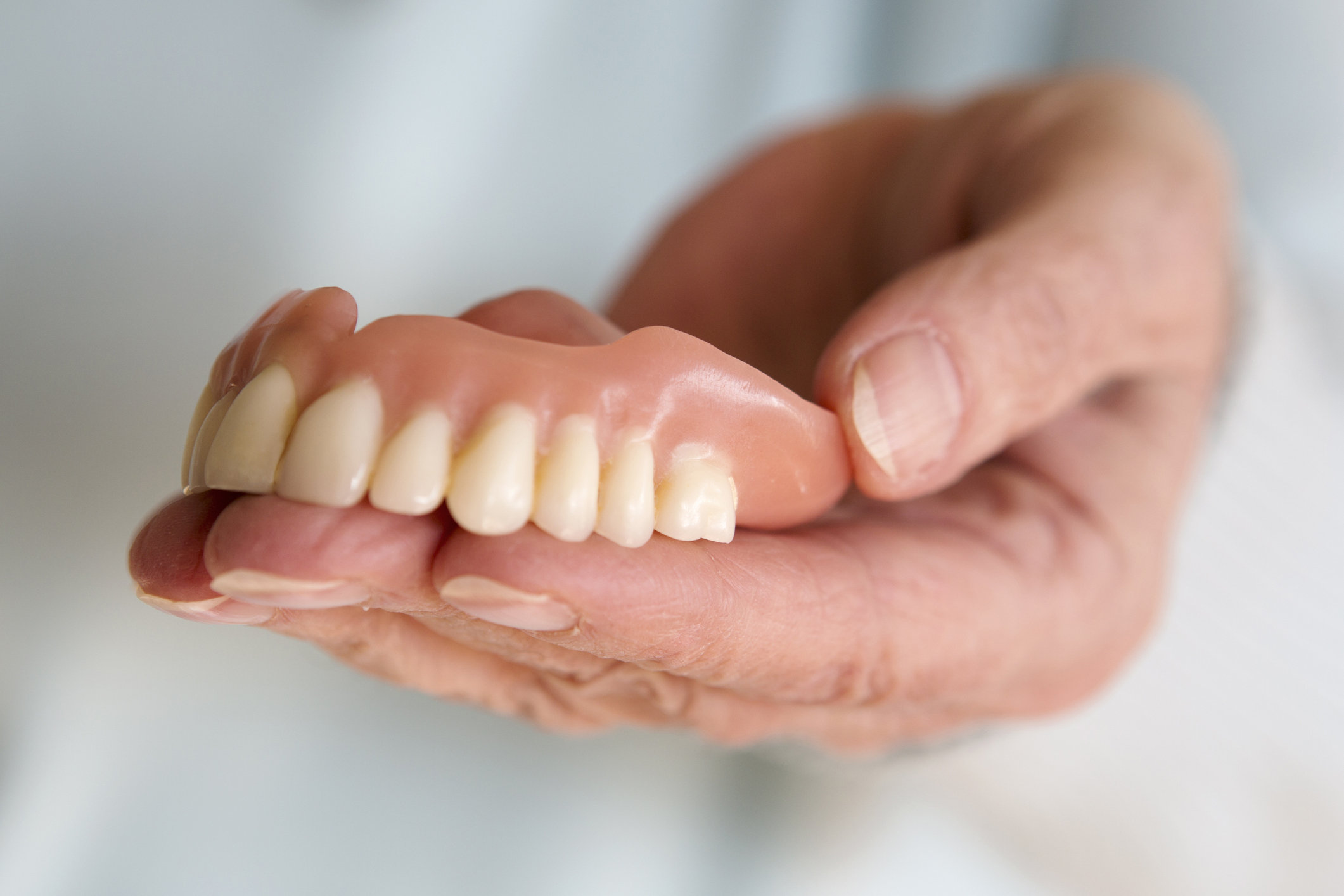 Closeup Of Womans Hand Holding A Teeth Denture
